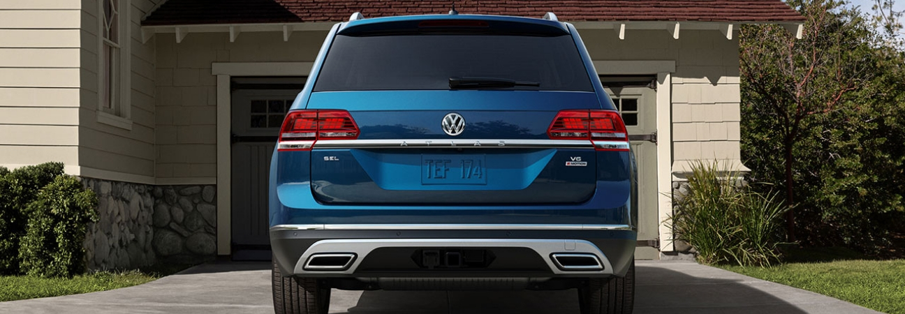 2019 Volkswagen Atlas in blue parked in the driveway of a suburban home.